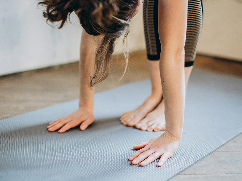 Woman in yoga pose with feet and hands on mat