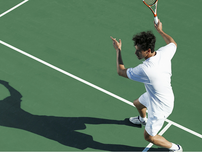 Man playing tennis on green court
