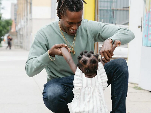 Young man playing with daughter on city street