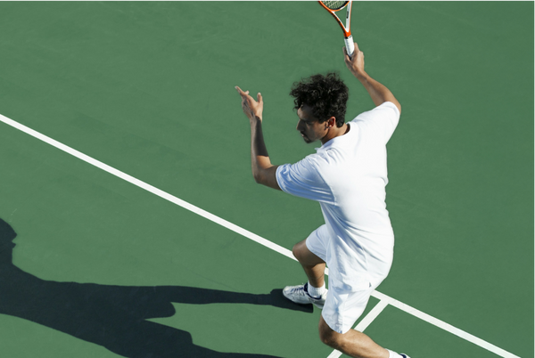 Man playing tennis on green court
